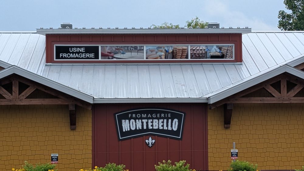 The exterior of a yellow and red painted building with a sign for Fromagerie Montebello.