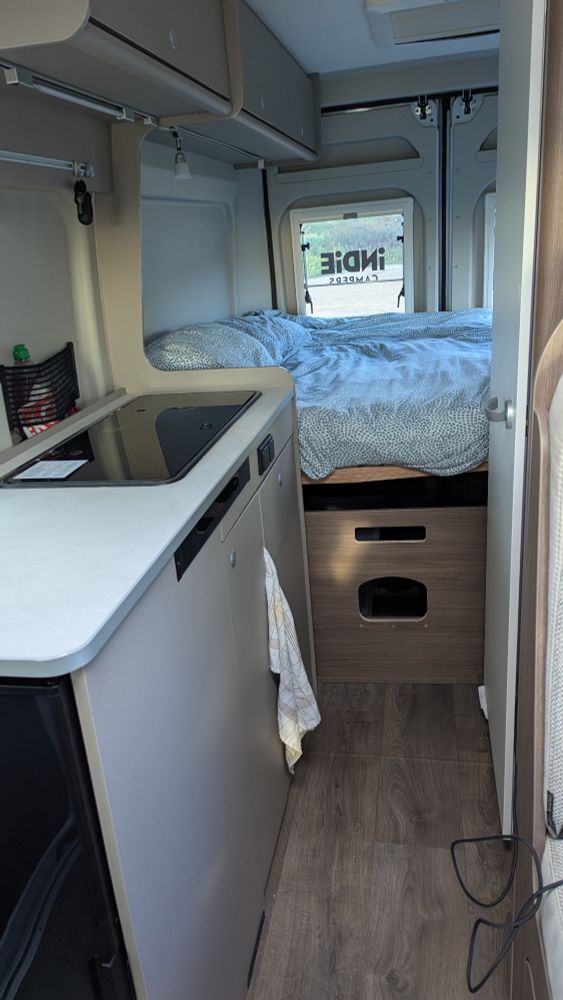 Inside view of campervan kitchen and bed.