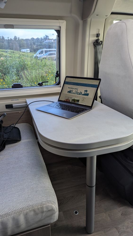 Campervan table and bench next to a window, with laptop on table