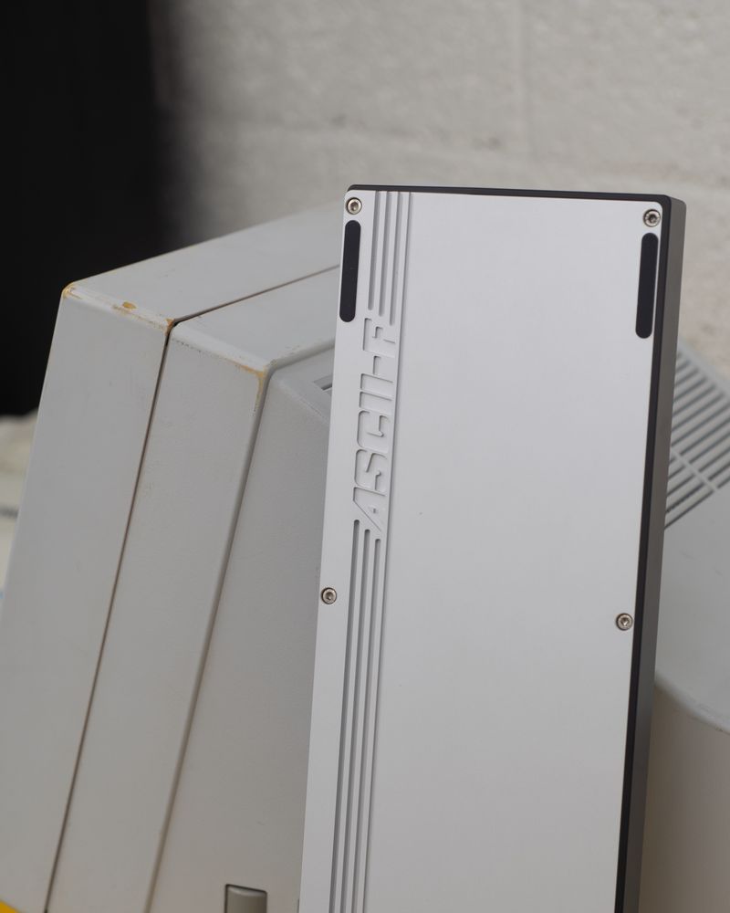 a picture detailing the bottom engraving of “ASCII-F”, the board is propped up against the Wyse monitor. 