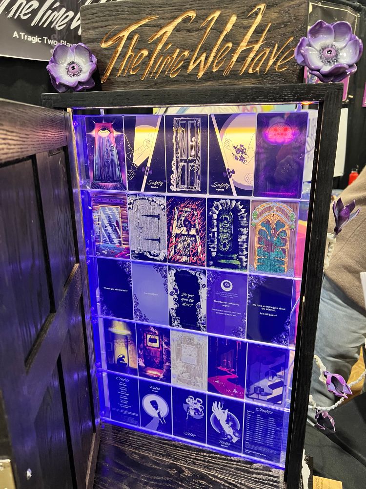 A desktop sized black door open with cards from The Time We Have mounted inside