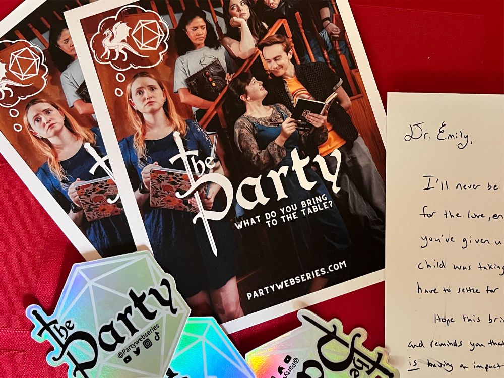 A photograph of promotional materials for The Party web series along with a cropped out note addressed to Dr. Emily.