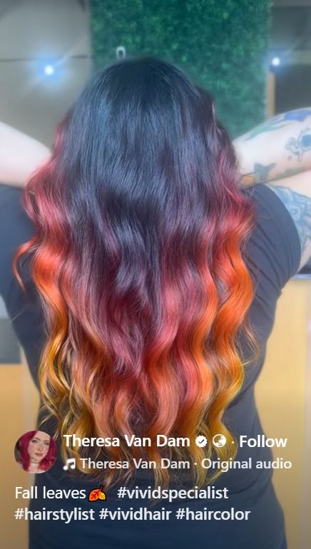 Long wavy hair coloured in blended shades of yellow, orange, plum and dark purple/black with the darkest top and central and the rest lightening the more outer and longer that the hair is.