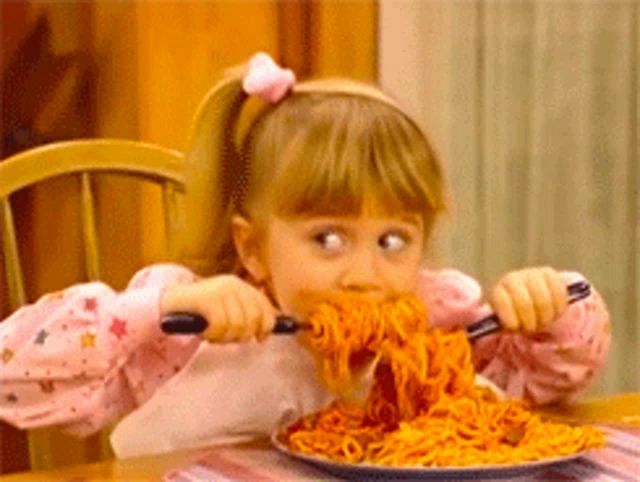 a little girl is eating a plate of spaghetti with a fork .