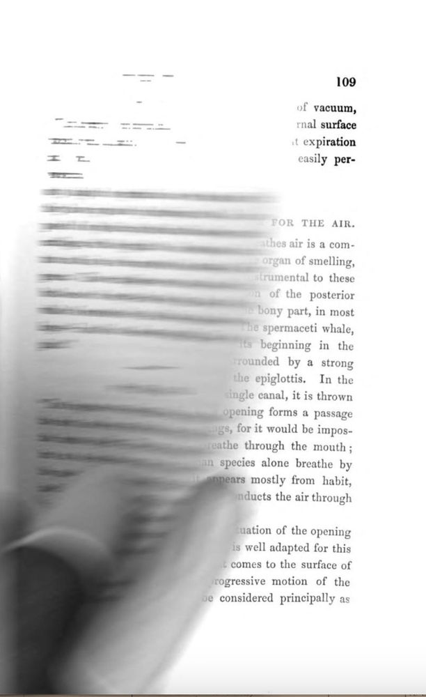 a hand wearing protective finger sheaths is turning a page. The page being turned is blurry.