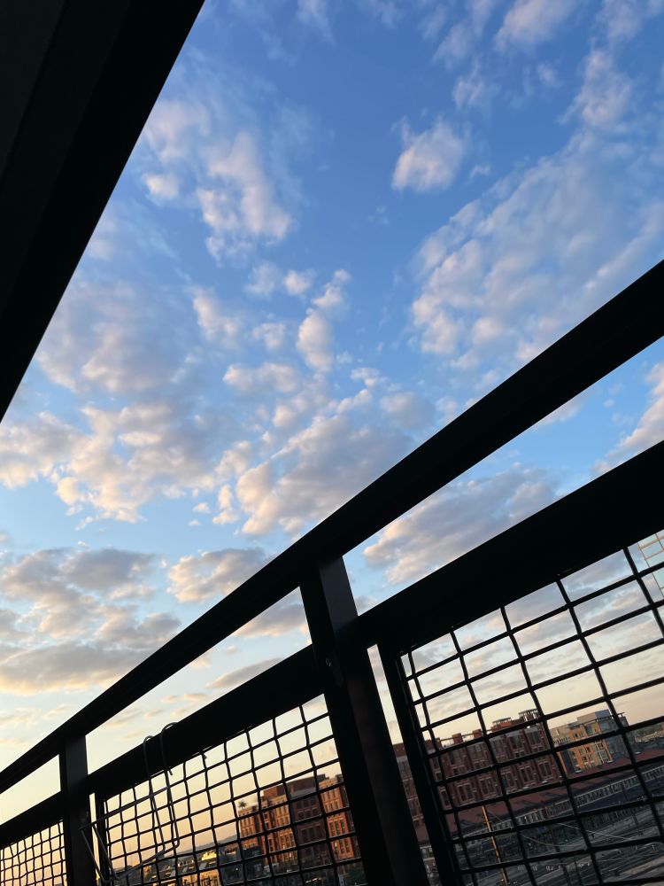 Beautiful clouds just after sunrise from a DC balcony, with some buildings and train tracks in the background. 