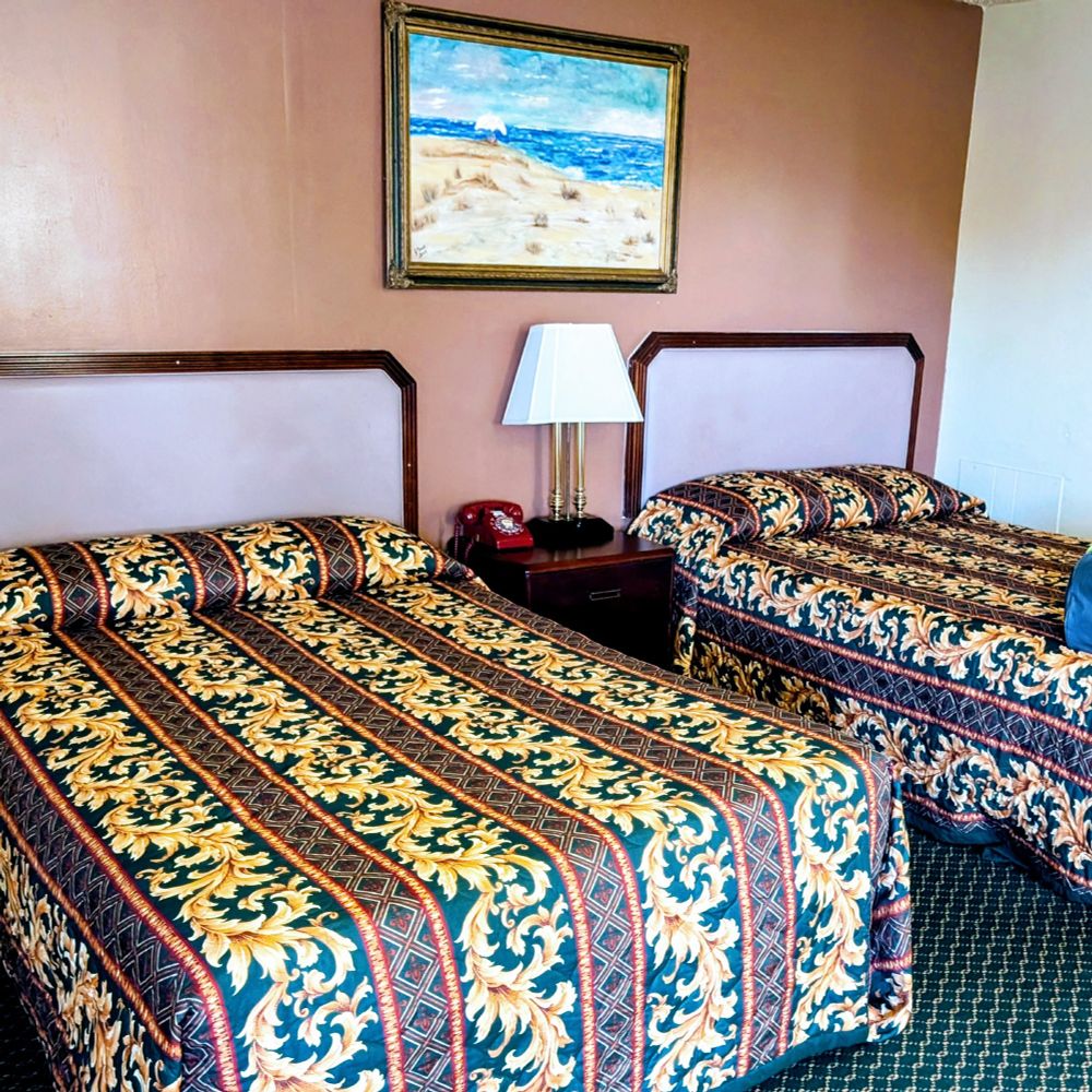 Two full sized beds with some wild patterned bedspreads.