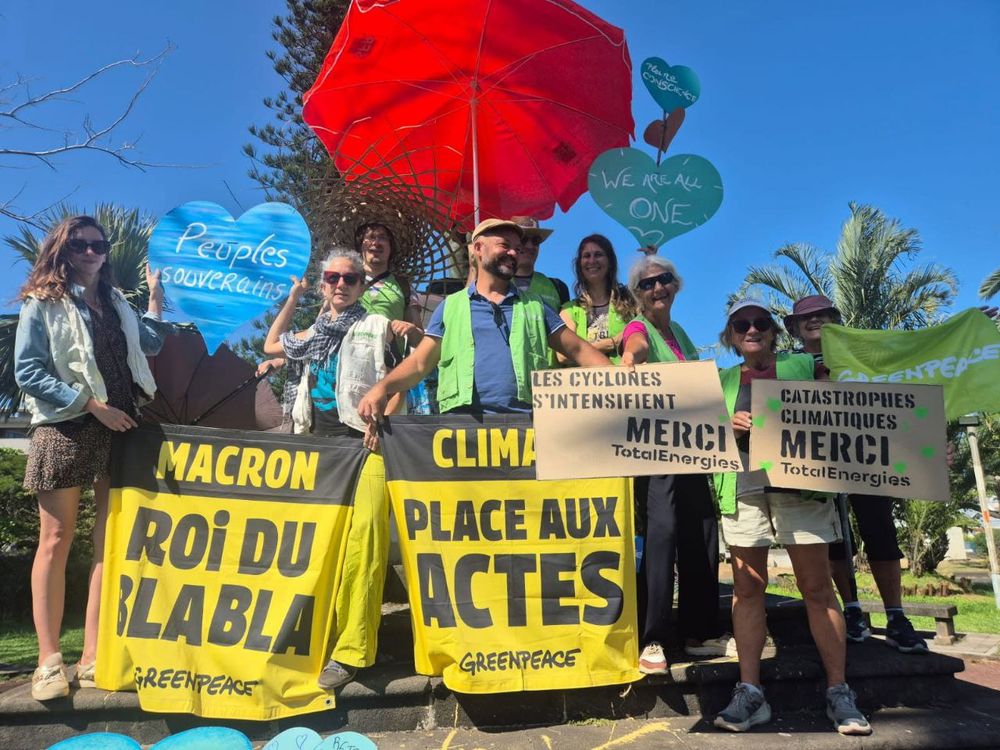 Photo de la marche des Résistances à Staint-Pierre (Réunion). Des militant·es posent en tenant des bannières "Macron, roi du blabla", "Climat, place aux actes", "Catastrophes climatiques, merci TotalEnergies", Les cyclones s'intensifient, merci TotalEnergies"