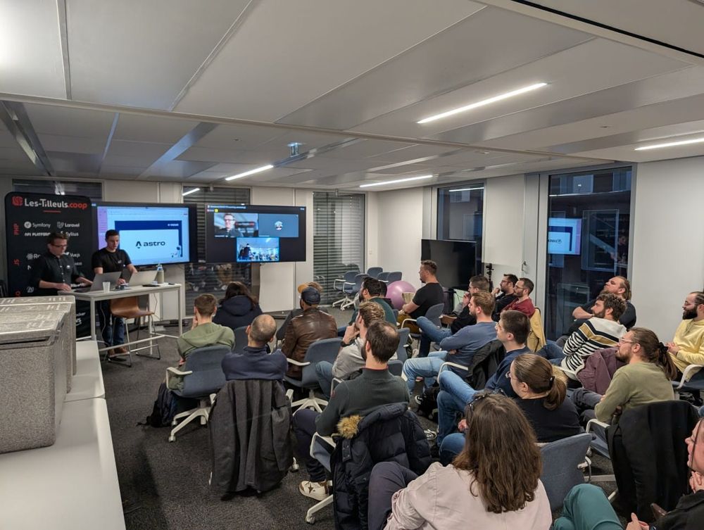 Meetup avec deux conférenciers, face à un auditoire assis dans une grande salle de réunion