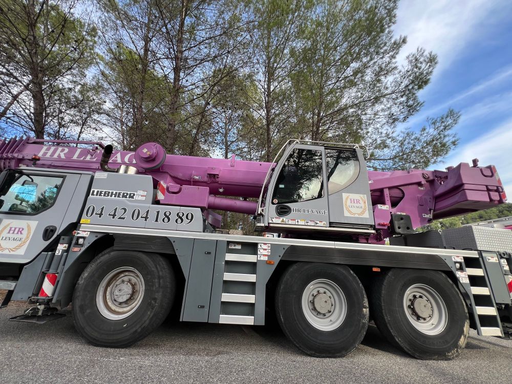 Photo of a large crane truck, the crane part is purple.