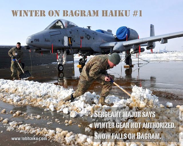 haiku is presented on a photo of two deployed U.S. airmen attempting to clear the snow off the tarmac, using only light snow shovels. They are not wearing coats or gloves. In the background, an A-10 "Thunderbolt II" jet is parked.