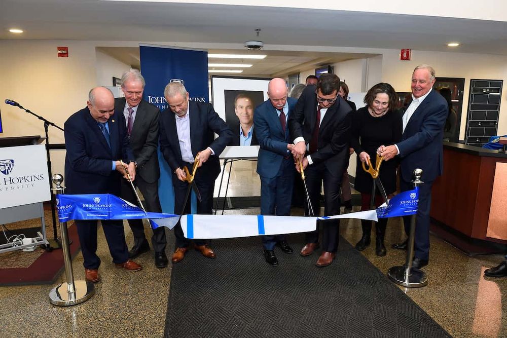 A group ribbon cutting in front of a portrait of Jeremy Walston.
