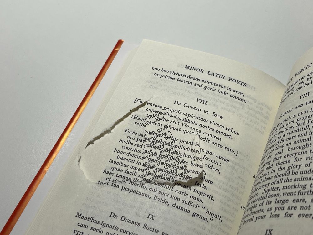 A partially torn page that has been printed on twice in a copy of LOEB's 'Minor Latin poets'