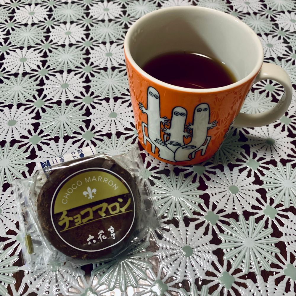 オレンジ色のマグカップと六花亭のチョコマロンの写真