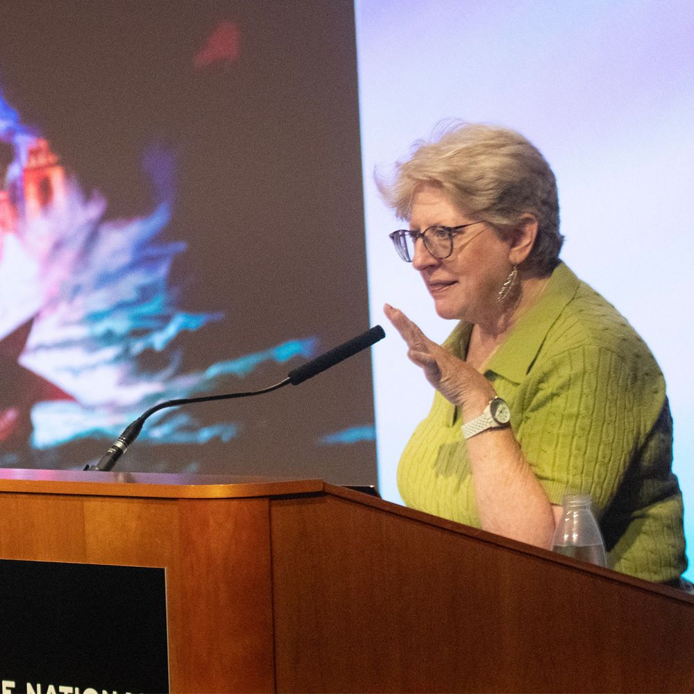 Westmoot Keynote Speaker, Janet Brennan Croft, delivers the Closing Keynote at a lectern, with a presentation screen visible behind her.