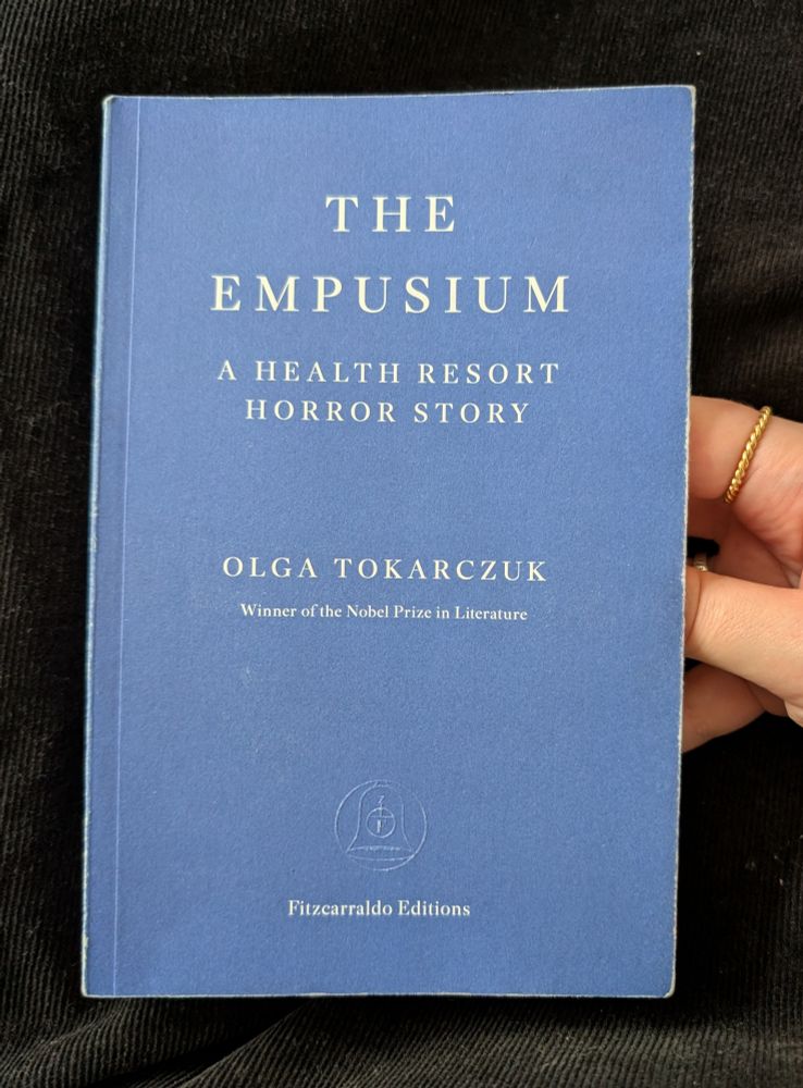 The Empusium, A Health Resort Horror Story by Olga Tokarczuk. Blue Fitzcarraldo Editions book against a black background. 