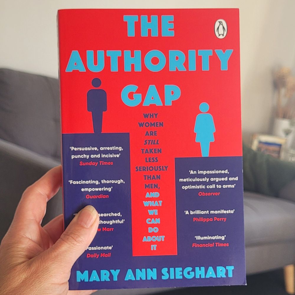 Photo of a book cover. It is red and blue and  the title reads 'The Authority Gap: Why women are still taken less seriously than men and what we can do about it.'
