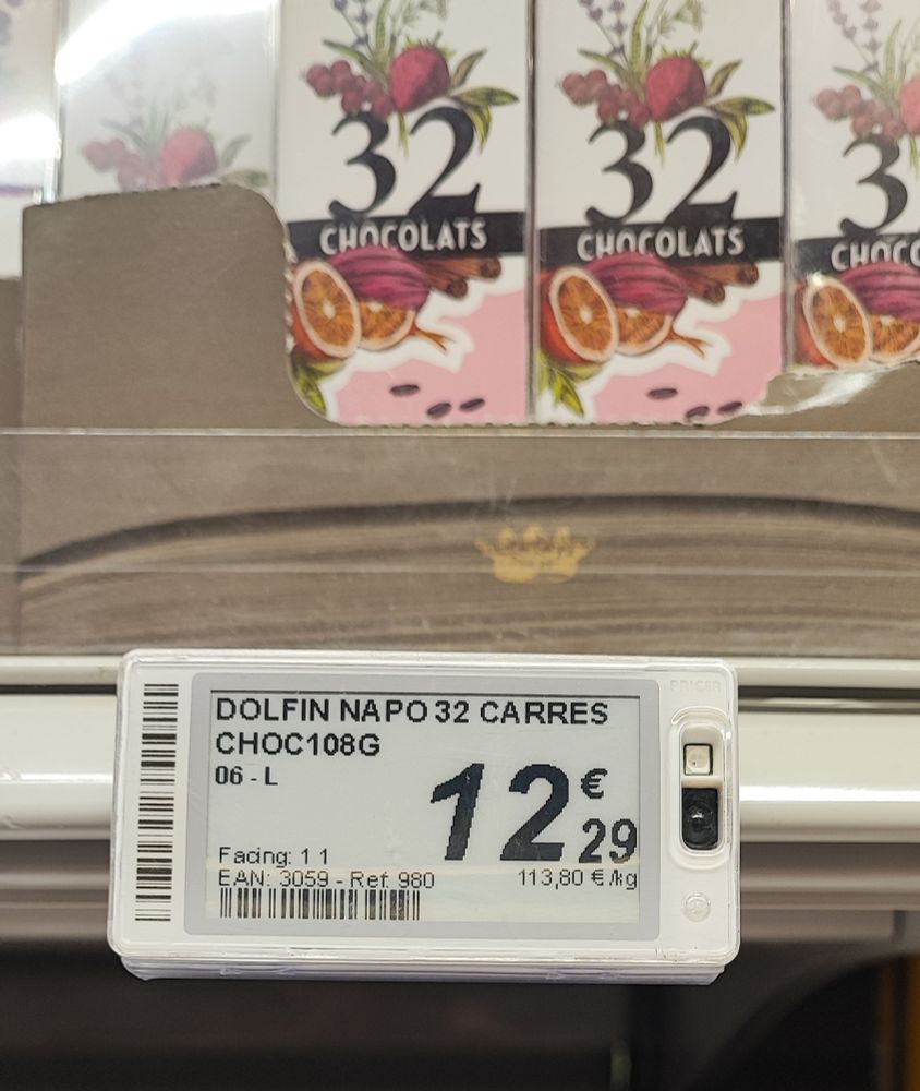 A photograph of chocolates in boxes on a supermarket shelf with the price below. The price is 114 euros per kilogram.