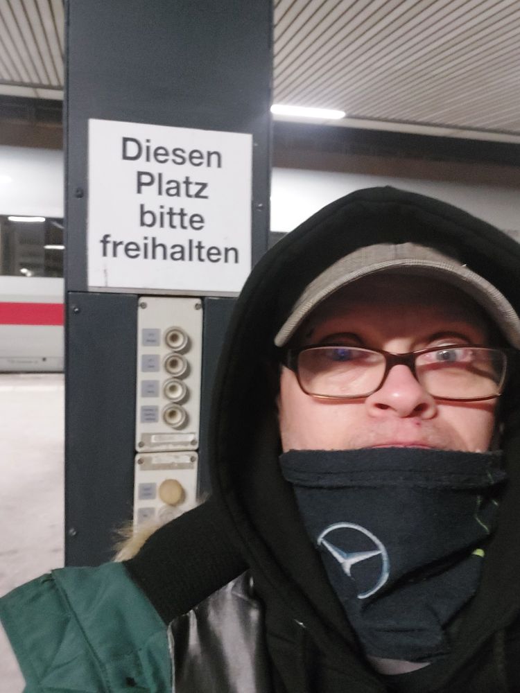 Mann steht vor einem Schild mit Text: Diesen Platz bitte freihalten 
