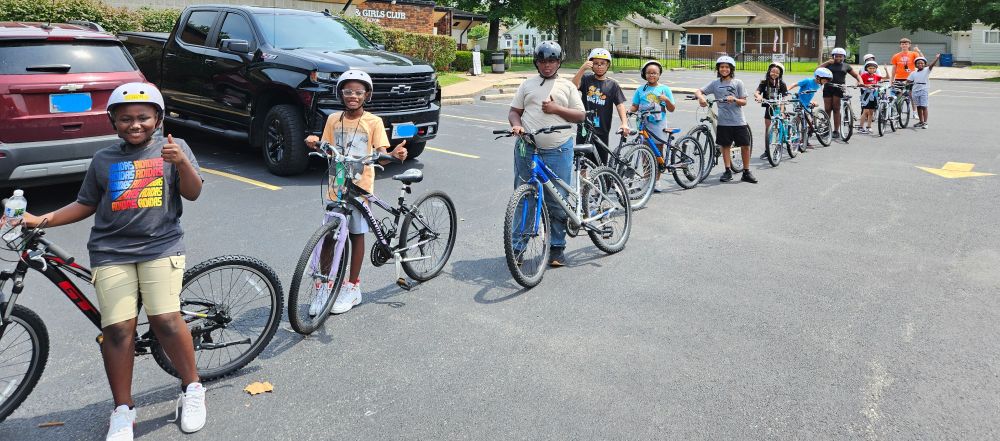 A group of 12 Alton-based Earn-A-Bike students pose with their thumbs up after helping unload the BWorks truck that carried their individually chosen bikes to Day 4 of their six-session class on Tuesday.