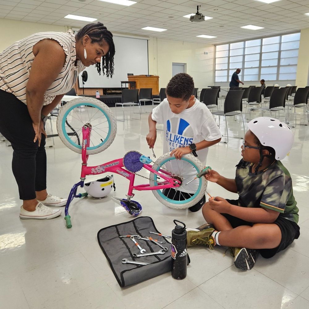 Two brand-new students and a helper dig into a BWorks puzzle-bike activity Tuesday evening at Heman Park Community Center.