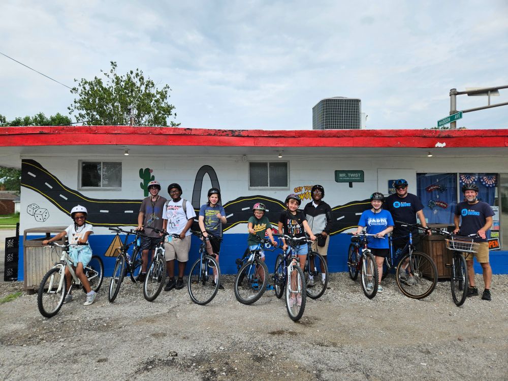 Eight Earn-A-Bike students and their BWorks helpers get ready for some more bike riding in Wilson Park and along Granite City streets and trails Saturday afternoon after enjoying some ice cream and sherbet at Mr. Twist. Behind them with their bikes is a Route 66 mural that includes a rendering of the Gateway Arch.