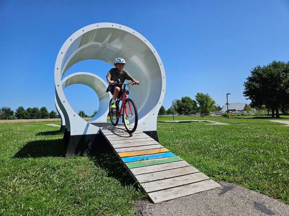 A Boulevard Park-based Earn-A-Bike student pedals through a tunnel at Kinetic Park.