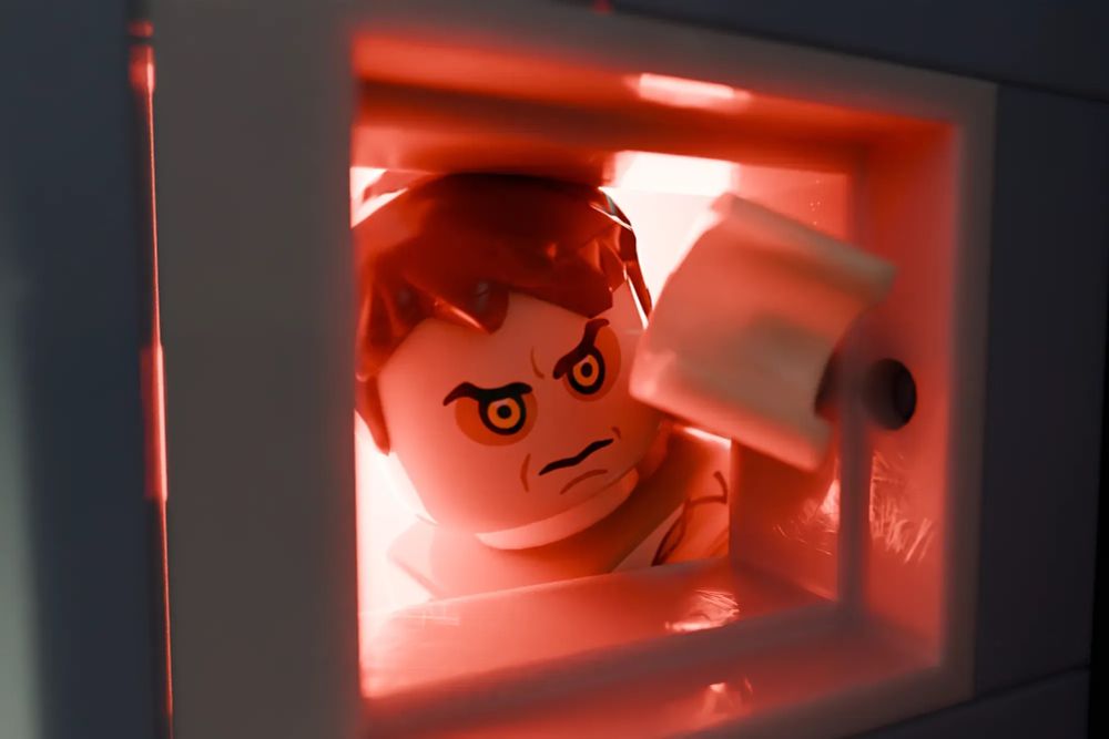 a close up of LEGO Eugene Tooms peering out of an air vent into Mufflers office