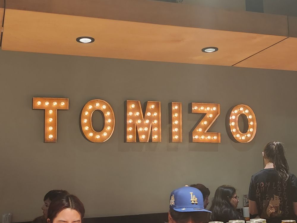 Light up letters on the wall of a ramen joint called Tomiso. IBut the kerning makes it look like T  O MIZ O.