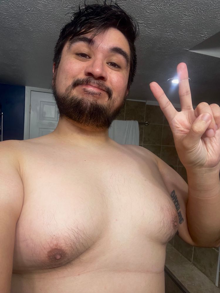 Shirtless Chicano man gives peace sign