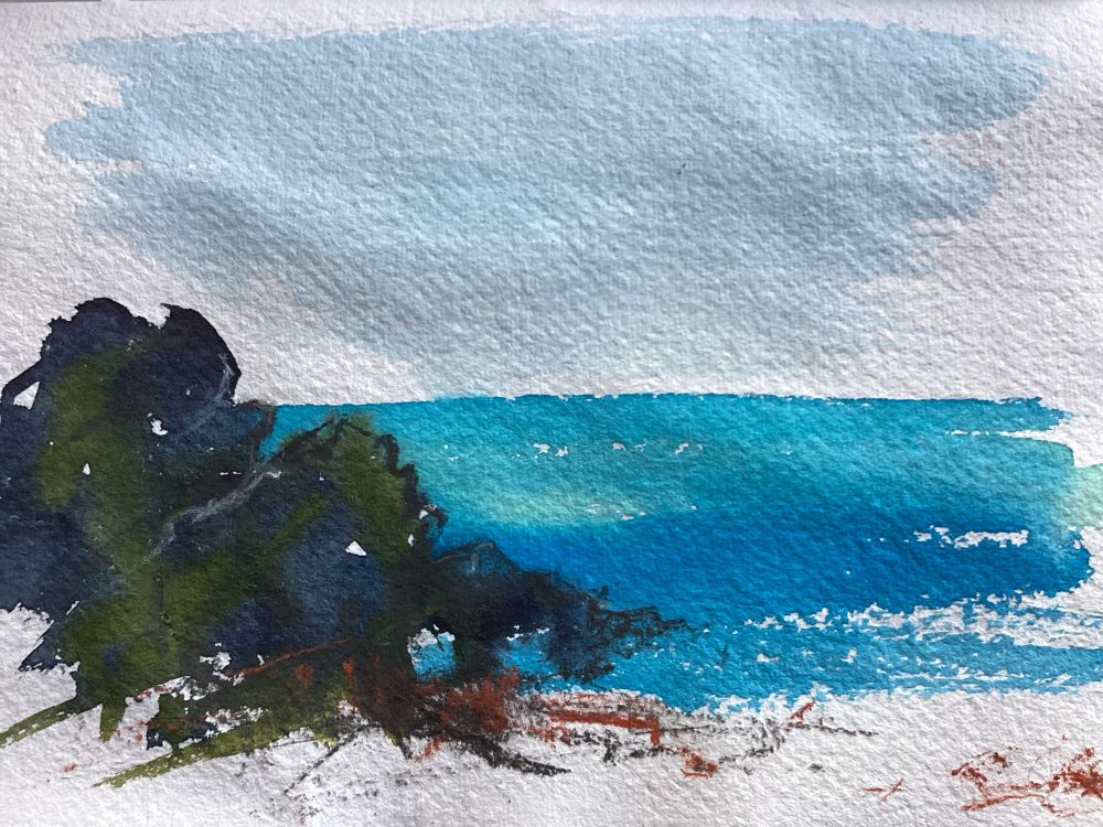 A painting in a sketchbook of the very blue sea and some dark rocks 