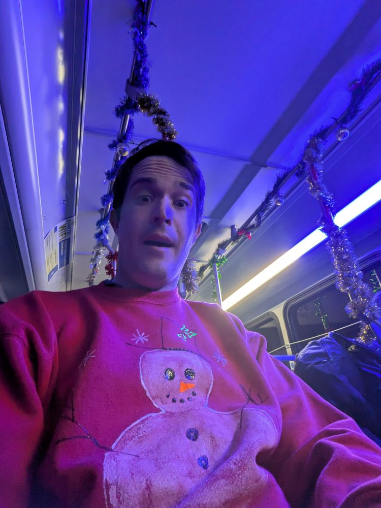 Selfie with a snowman sweatshirt and the Cincinnati Metro holiday bus decorations in the background. 