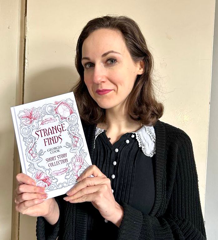 Photo of a woman holding a copy of a book titled “Strange Finds, Short Story Collection, Georgia Cook”