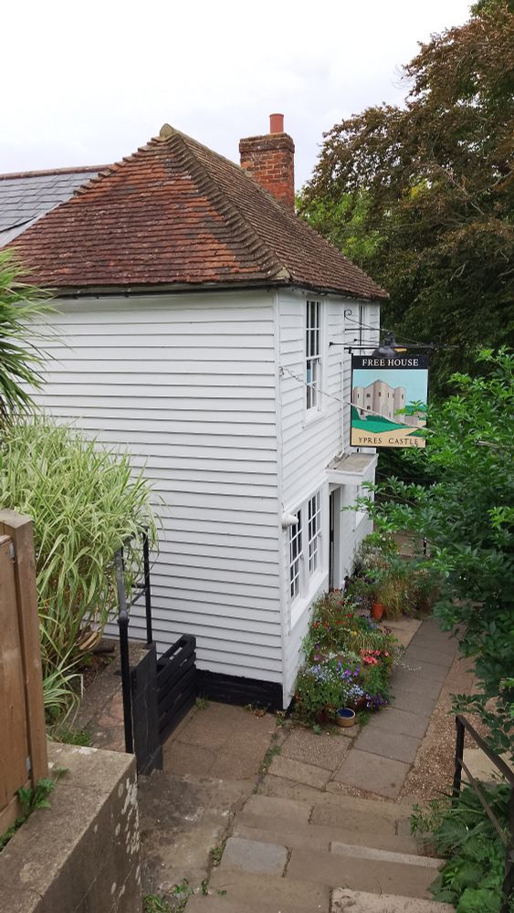 Ypres Castle Inn, Rye. White weatherboarded pub at the bottom of some steps, lots of flowerpots outside 