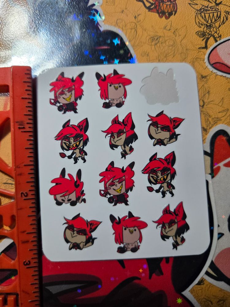 A photo of a mini sticker test sheet I did, it's 3 inches long and has 12 mini alastor stickers on it