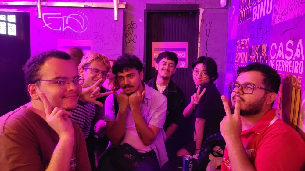 em ordem de esquerda pra direita, vic @bjorkiller, andre @andredecorating, tonton @rezdogy, gustavo @internautazinho, fernando @fandsquem e math @hashtagmath.
estao em uma sala rosa fazendo poses viadas