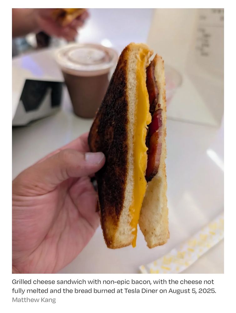 A photo in the article above showing a hand holding what the caption describes as Grilled cheese sandwich with non-epic bacon, with the cheese not fully melted and the bread burned at Tesla Diner on August 5, 2025.
Matthew Kang