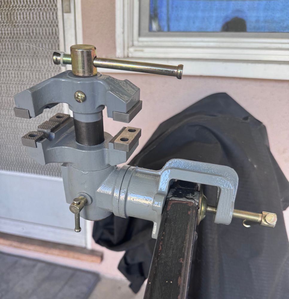 A matte silver gice grip that is attached to a hand rail by a clamp. 