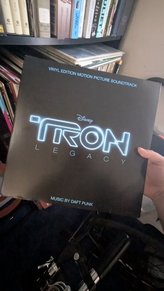 The Tron Legacy soundtrack on vinyl, someone is holding the album in front of a bookcase 