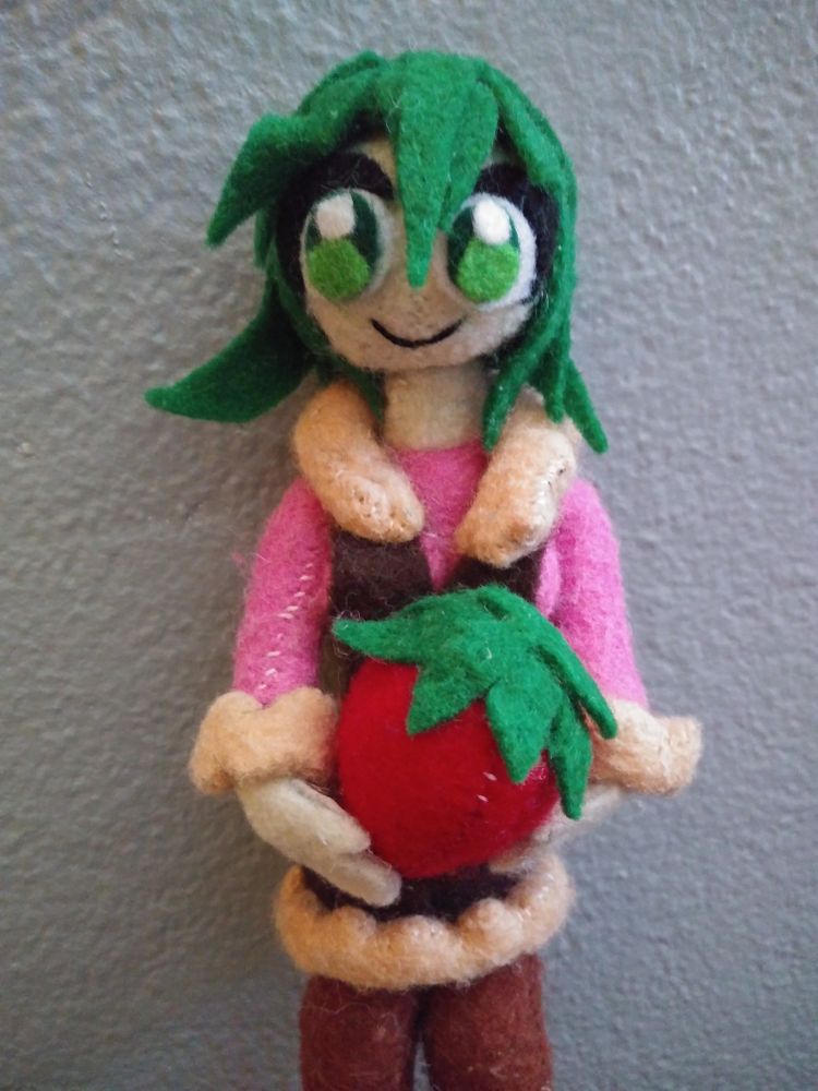 Felt and wire version of calamari sundae facing directly at the camera while holding a big felt strawberry (without chocolate squid hat on)