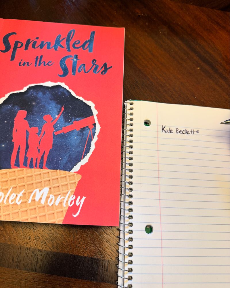 Book Sprinkled in the Stars next to notebook with the word Kate Beckett written on the page. 