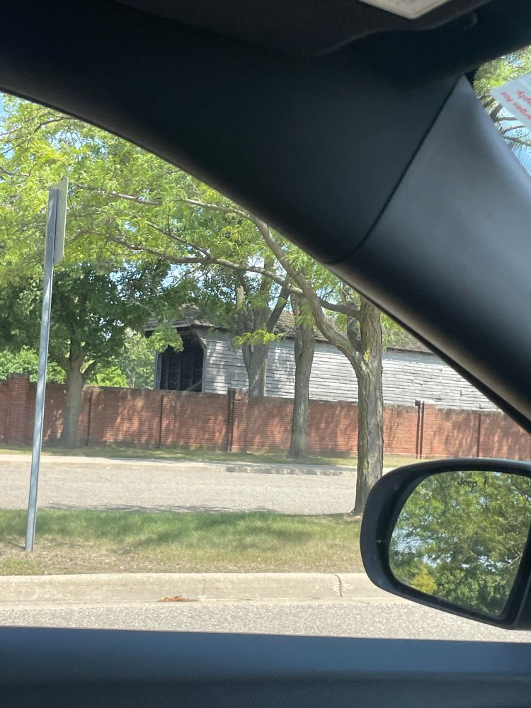 Covered bridge behind a brick wall taken from a car driving by 