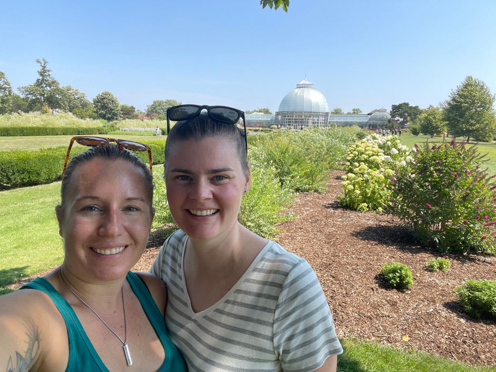 Fiancée and me standing in front of some gardens w a conservatory dome in the distance 