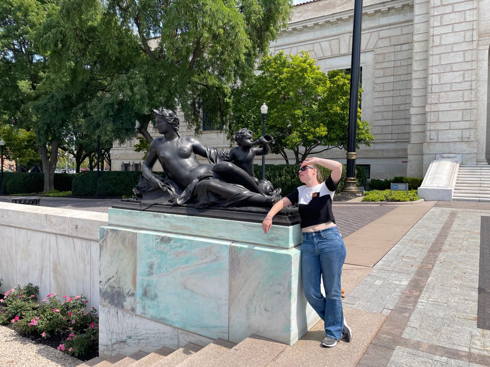 Fiancée flopping backwards dramatically next to a sculpture of a lounging lady