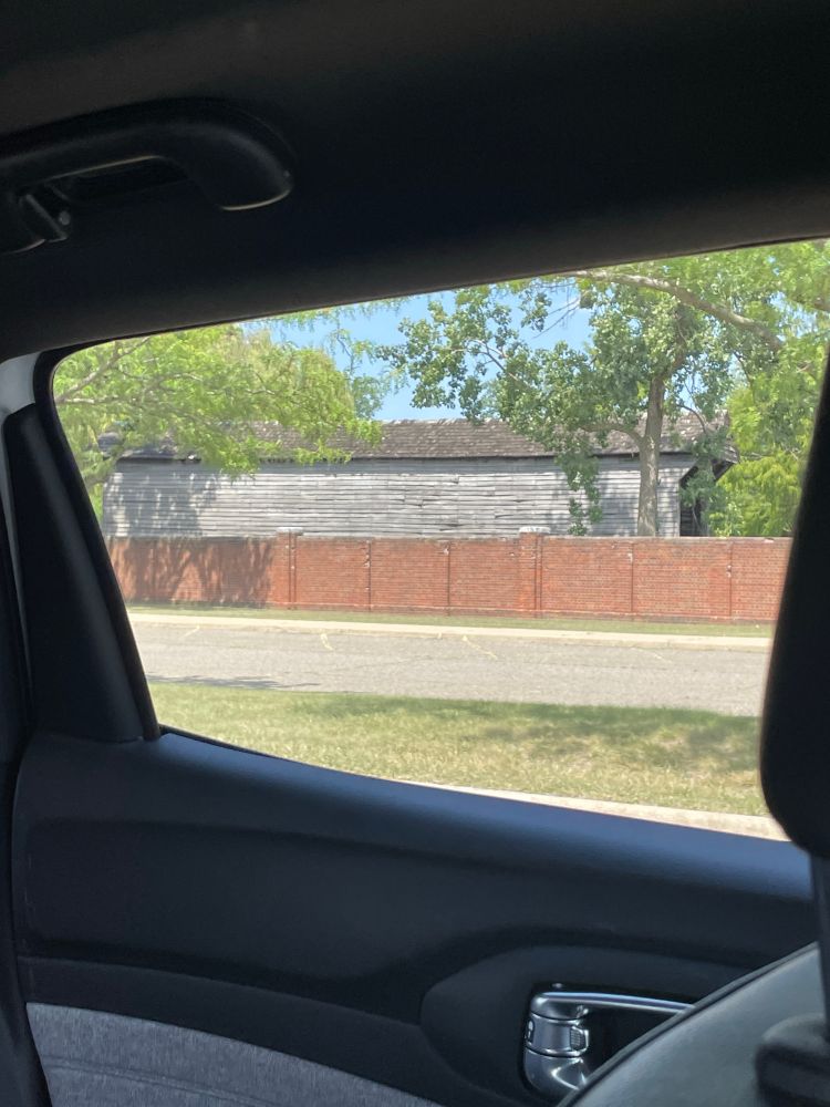 Covered bridge behind a brick wall taken from a car driving by 
