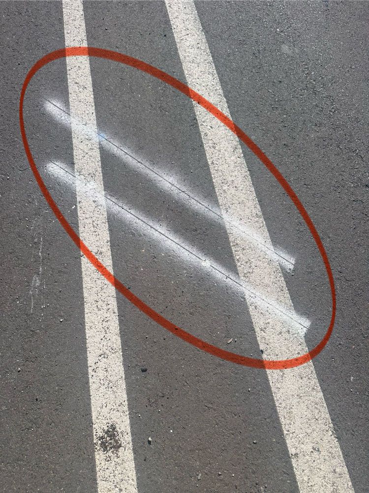 Two score marks and white paint placed parallel to each other, and diagonally over two white lane buffer markings