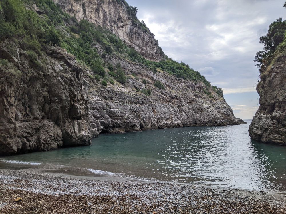 Steep-walled narrow beach covered with shells.