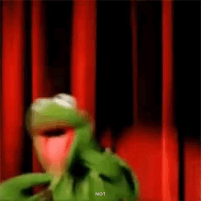 kermit the frog is standing in front of a red curtain and making a funny face .