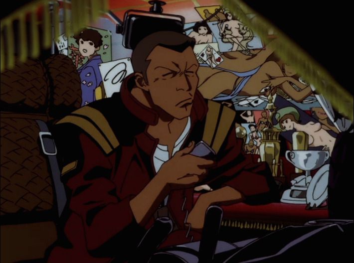 A dark skin man holding a device in his hand. He is wearing a red jacket. Behind him are photos of suggestive poses of women.