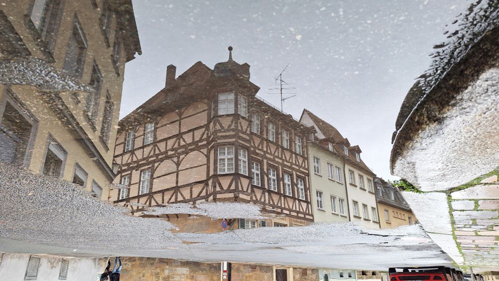 Ein Fachwerkhaus als Spiegelung in Pfütze, Foto um 180 Grad gedreht 